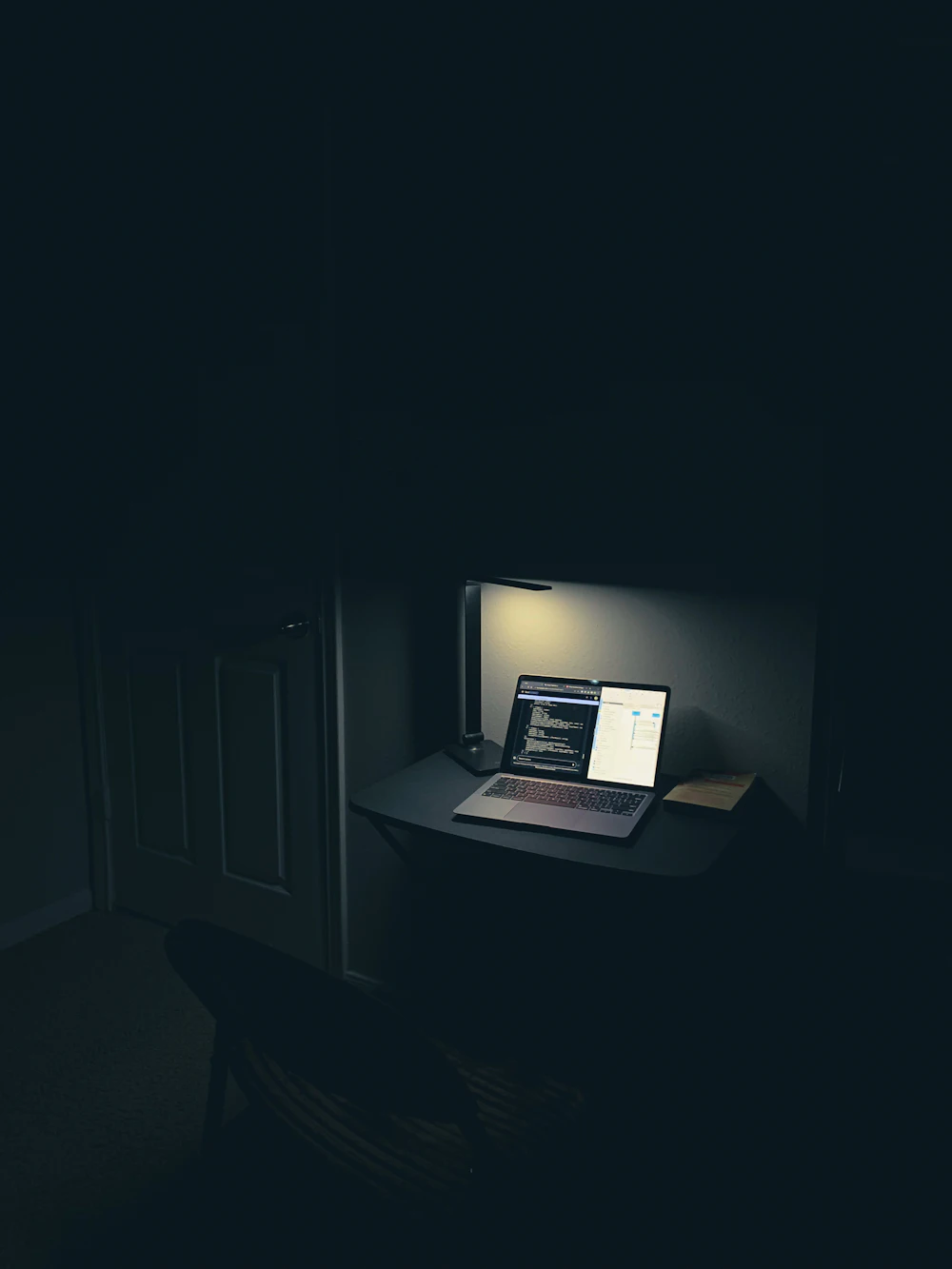 Laptop pe un birou minimalist, într-un spațiu de lucru cu lumină discretă